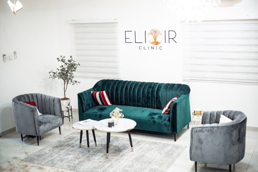 Elixir Clinic’s waiting lounge, with an emerald sofa, two armchairs and the clinic’s signage on the wall.